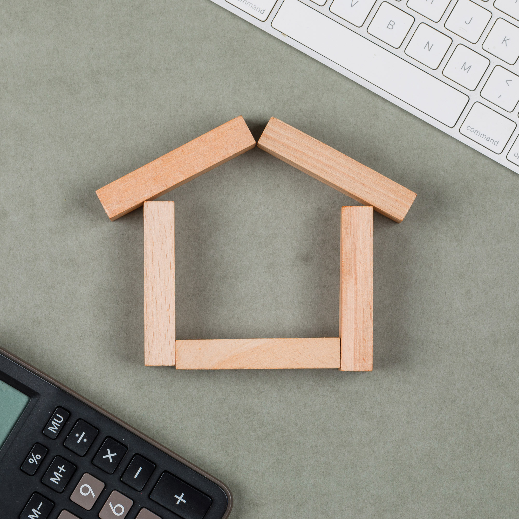 Immobilienkonzept mit Holzklötzen, Taschenrechner, Tastatur auf grauem Hintergrund flach legen.