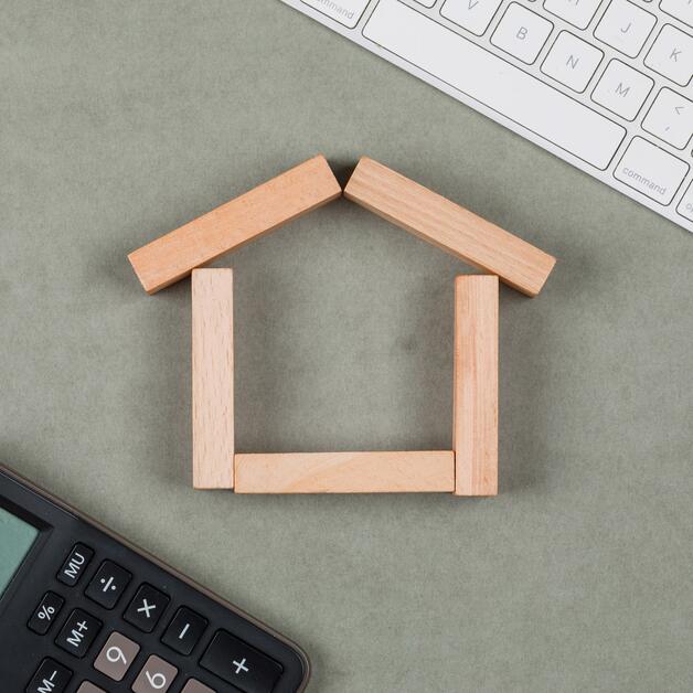 Immobilienkonzept mit Holzklötzen, Taschenrechner, Tastatur auf grauem Hintergrund flach legen.